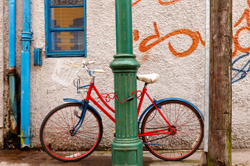 Retro bicycle locked to a green column in an urban setting with graffiti in Ireland