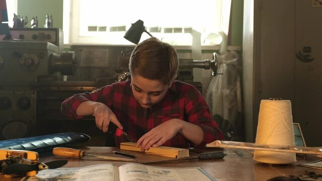 A teenager works with a stationery knife and a file