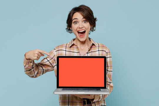 Young smiling happy woman 20s wear brown shirt hold use work point finger on laptop pc computer with blank screen workspace area isolated on pastel plain light blue color background studio portrait