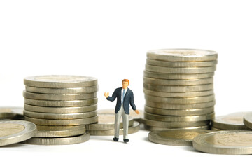 Miniature people toy figure photography. Financial plan concept. A shrugging businessman standing in between two coin money stack. Isolated on white background