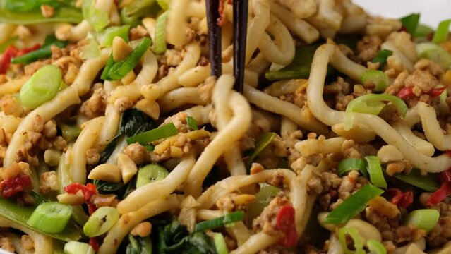 Eating Pork, peanut noodles with pak choi, mangetout and red chili. Asian food
