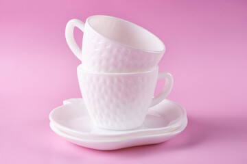 Two beautiful white cups in the shape of strawberries and two saucers on a pink background. Empty dishes.