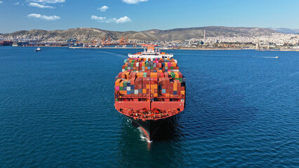 Aerial drone photo of huge container ship leaving logistics and container terminal of Perama,...