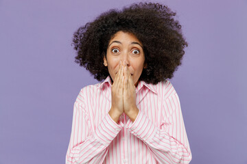 Fototapeta na wymiar Young shocked surprised amazed astonished impressed woman of African American ethnicity 20s wearing pink striped shirt cover mouth with hands isolated on plain pastel light purple background studio.