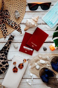 Flat lay with copy space of beach accessories with face mask and alcohol hand sanitizer gel on wooden background, pandemic covid travel concept, vertical photo