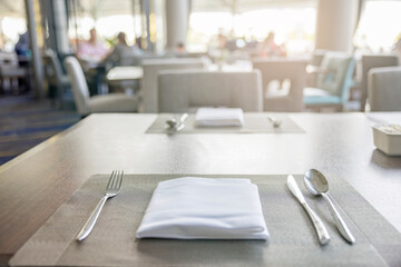 Table arrangement in an expensive haute cuisine restaurant. Fork, knife, spoon, silk napkin on bamboo mat.
