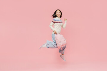 Full size happy excited teen student girl of Asian ethnicity in sweater hold backpack jump high do...
