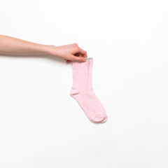 Female hand holding pair of pink modern trendy women's cotton socks on white background. Fashionable socks store. Socks shopping, sale, merchandise, advertisement concept