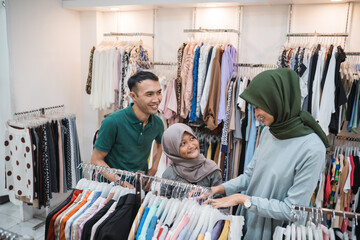 asian muslim family buying new clothes together in clothing store