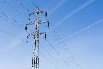 High voltage columns, in the background with blue sky and clouds. Prices of electricity, consumption, ecology.