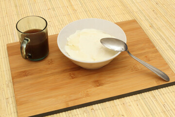 A bowl of Wedang Tahu or Kembang Tahu with a glass of ginger and palm sugar syrup on the left side