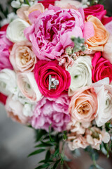 Obraz na płótnie Canvas Multicolor wedding rose bouquet Beautiful blossoming flowers in white, red, and pink colors Bride and Groom's rings on the flower petals Close up