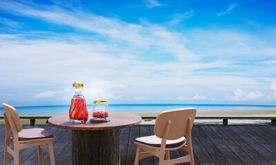 Brandy or whiskey liqueur in a luxury bottle. The table is made of wood. Wooden terrace on the beach, by the sea, clear sky during the day turquoise sea The sky has white clouds. 3D rendering