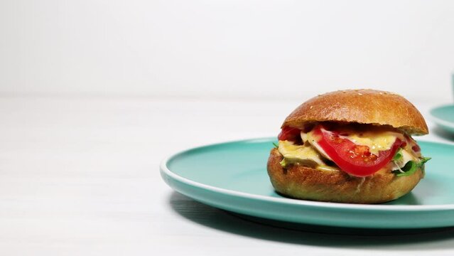 Bagel with chicken, tomato and cheese on wooden table.