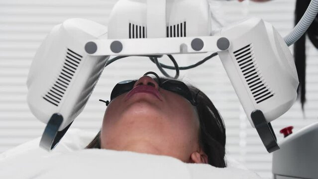 Young brunette woman getting modern facials - device descends over the client's face