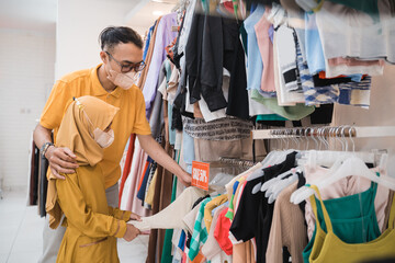 Fototapeta premium muslim father choosing shirt with daughter during shopping at fashion shop