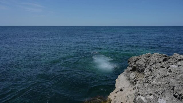 adult man jumping from rocky stone into water sea during summer vacation travel