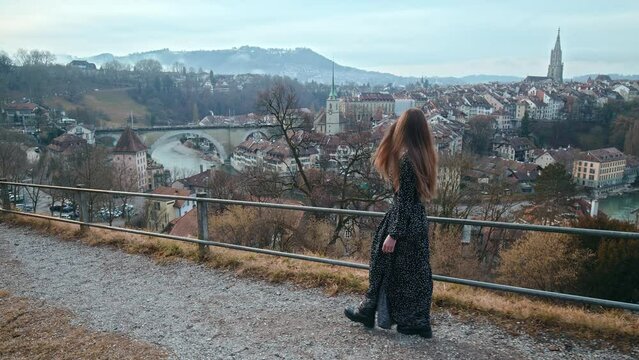 A fashionable girl in a dress walks towards the old town of Bern in slow motion. A woman exploring Bern the capital of Switzerland, a historic Swiss City with beautiful architecture.