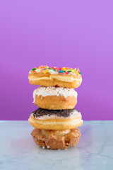 Four color donuts stacked in front of a bright purple background
