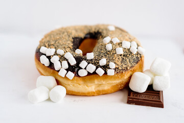 A smores donut with extra marshmallows and chocolate on a white background