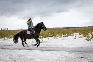 Fototapeta na wymiar Girl on a black horse. Walk with a horse through the countryside. Russia. Lipetsk 20.02.2022
