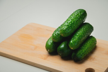 Several fresh green cucumbers on a wooden cutting board