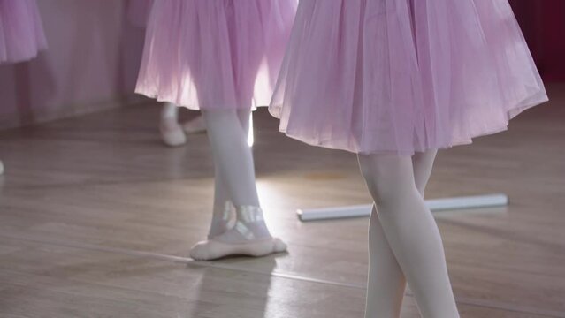 Ballet training - five girls in beautiful dresses training by the stands in the studio - standing in the position