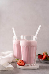 two strawberry milkshakes with strawberry pieces in a glass
