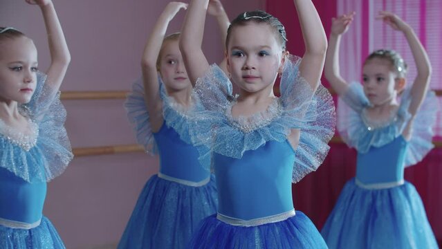 Ballet training - four ballerina girls in blue dresses spinning on the spot