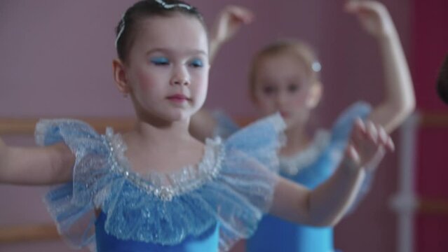 Ballet training - four ballerina girls in blue dresses walking on their toes forwards in a row and go to their positions