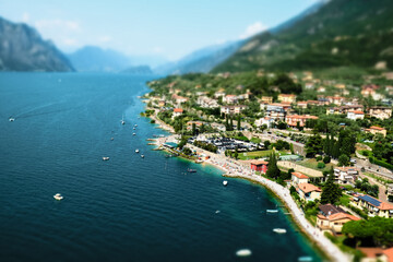 Miniature of small mediterranean town Malcesine and lake Garda, Italy, with boats, beach and mountains in the horizon during summer time