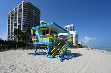 Fototapeta na wymiar Colorful lifeguard station on Miami Beach, Florida displaying medium hazard and dangerous marine life warning flags on clear sunny afternoon.