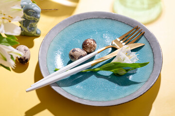  Table setting for celebrating easter. Plate, cutlery, eggs and spring flowers on the yellow table close up
