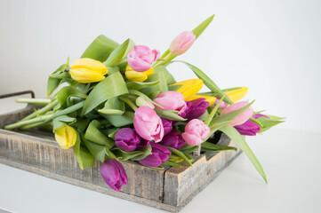 pink, yellow and purple tulips in a wooden tray