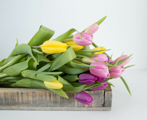 pink, yellow and purple tulips in a wooden tray