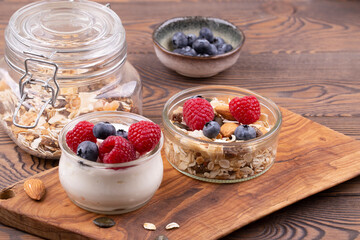 Homemade granola with nuts, raspberries and blueberries, yogurt on a wooden rustic table, copy space. healthy breakfast