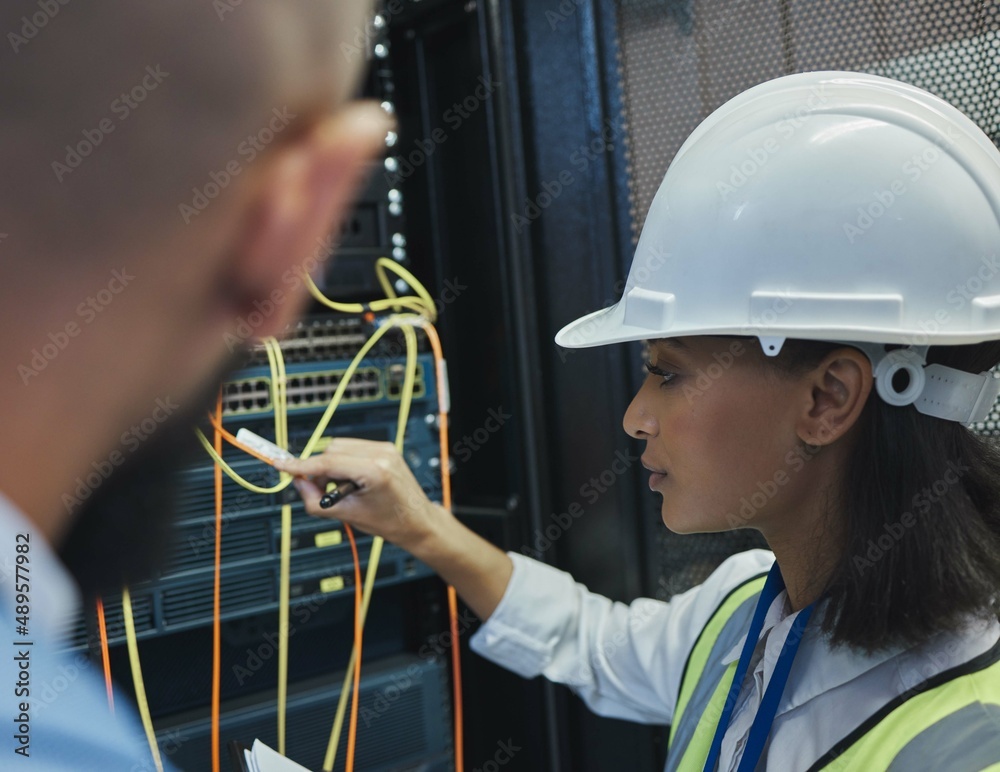 Poster gotta get this right. shot of two workers inspecting the electronic equipment in a server room toget