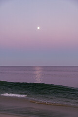 Full moon rises over the ocean at twilight