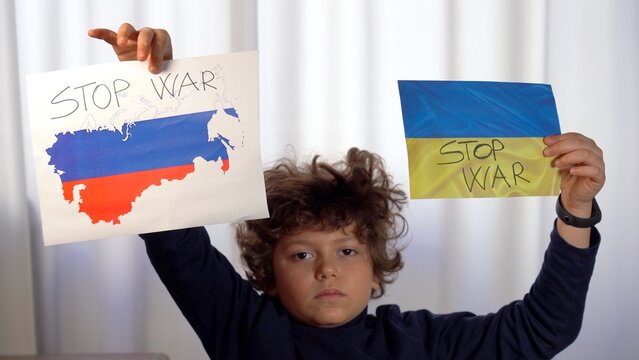 Boy child 7 years old protest against the war between Russia and Ukraine with sign stop war on a flag  - start of the conflict in Europe in territories close to NATO