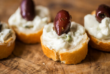 Small piece of bread with tzatziki spread and olive,closeup.