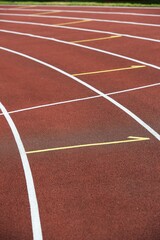 Running tracks. Red tartan on an athletic stadium. White and yellow lines. Sunny sunny day.