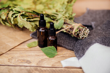 Cosmetics for spa treatments and baths on a wooden table with a birch broom.