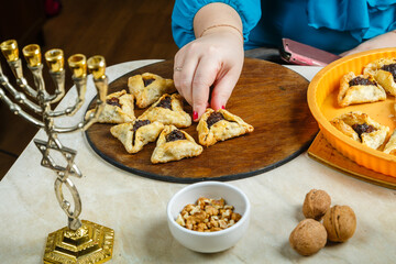 A Jewish woman stacks gomentashi cookies for the Purim holiday on a wooden board.
