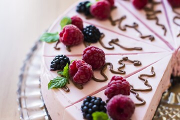 Raspberry creamy cake on a glass tray, laid on a table.