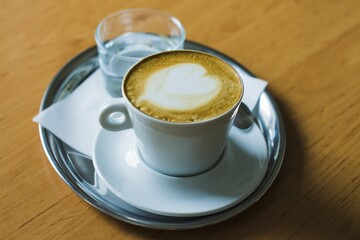 Coffee with water on a stainless steel mat, laid on a wooden table.