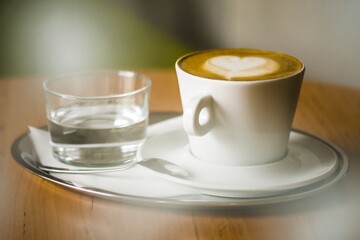 Coffee with water on a stainless steel mat, laid on a wooden table.
