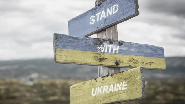 stand with ukraine text quote on wooden signpost outdoors, written on the ukranian flag. Peace and unity concept.