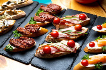 different sandwiches on a black board on a table in a cafe