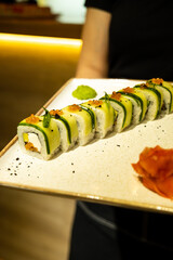 green rolls with cucumber on a stand in hands at sunset