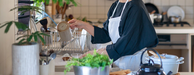 キッチンで食器の洗い物をするエプロン姿の女性